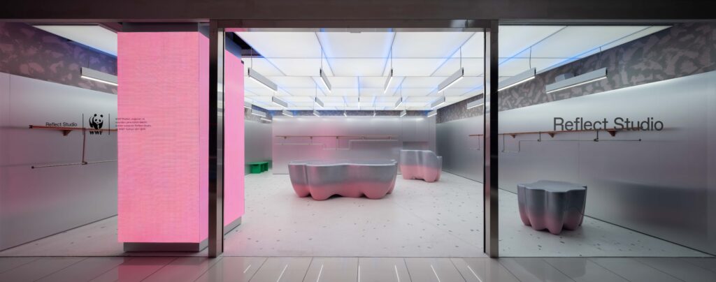 Storefront with glass facade, pink interior accents, and sculptural furniture
