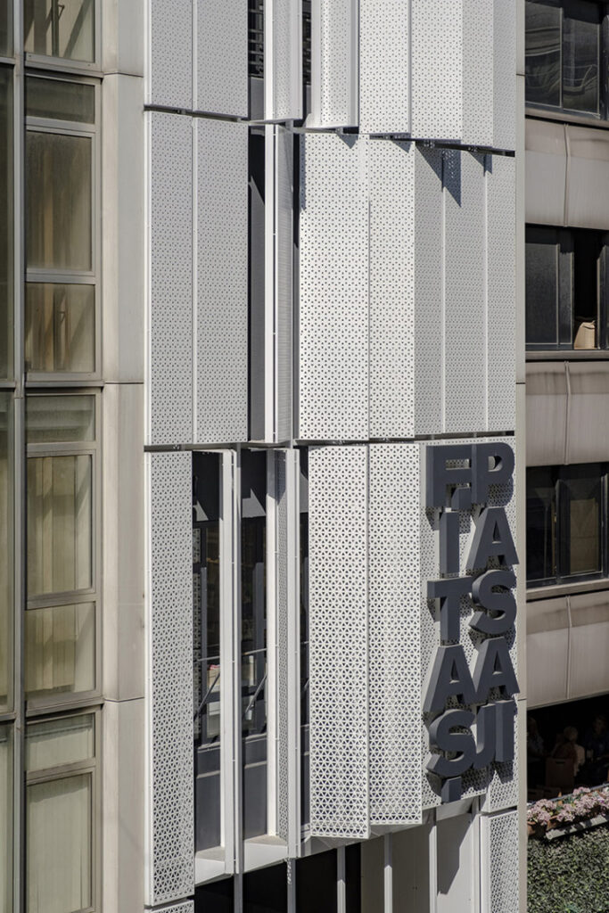 Adaptive reuse project with perforated white facade panels on a transformed historic arcade building